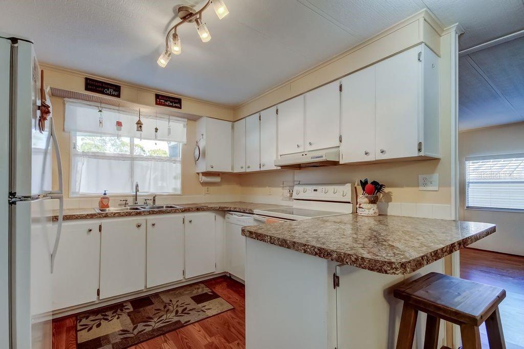 A kitchen with white cabinets, a granite-look countertop, and a small breakfast bar — 3430 TIKI DRIVE, HOLIDAY, FL