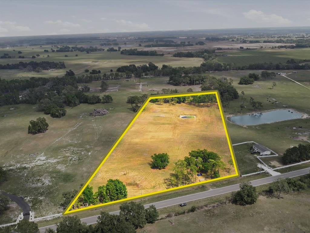 An aerial view shows a large, cleared, trapezoidal plot of land bordered by a road — COUNTY ROAD 469, CENTER HILL, FL