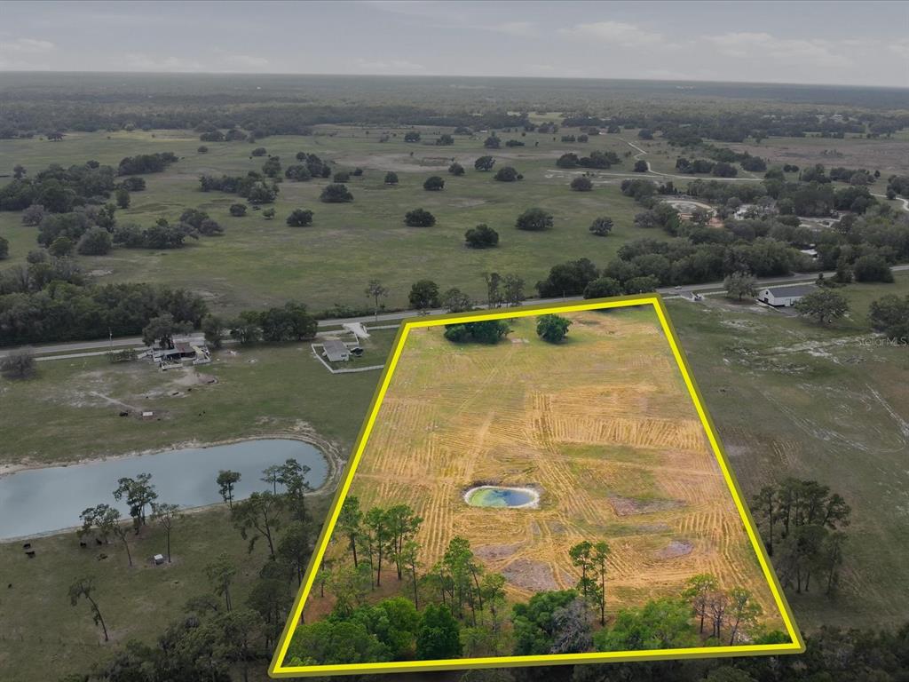 An aerial view shows a large, rectangular plot of land featuring a small pond — COUNTY ROAD 469, CENTER HILL, FL