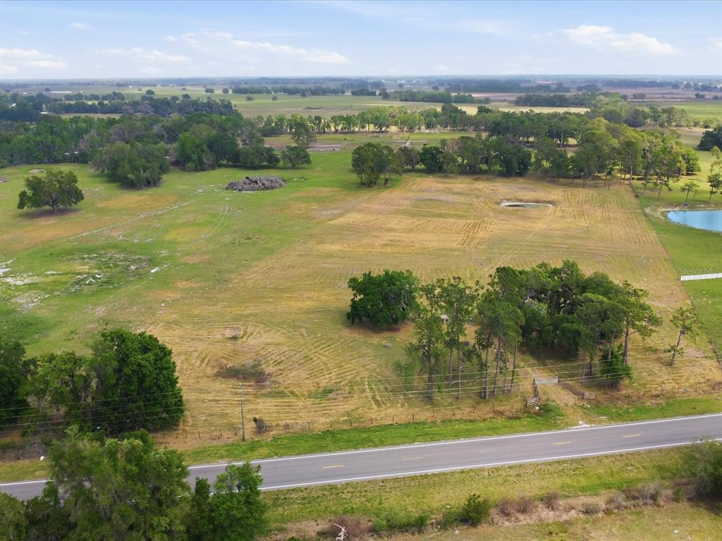 An aerial view shows a large, grassy rural lot bordered by a paved road — COUNTY ROAD 469, CENTER HILL, FL