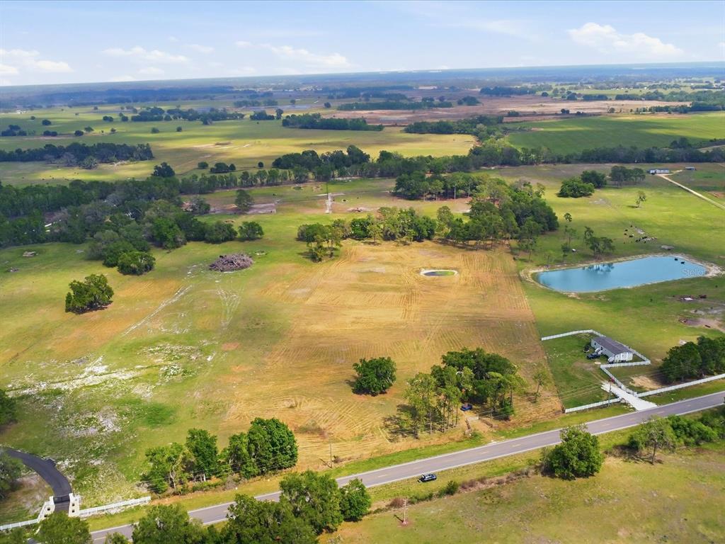 An aerial view shows a large, grassy rural lot with scattered trees and a small pond — COUNTY ROAD 469, CENTER HILL, FL