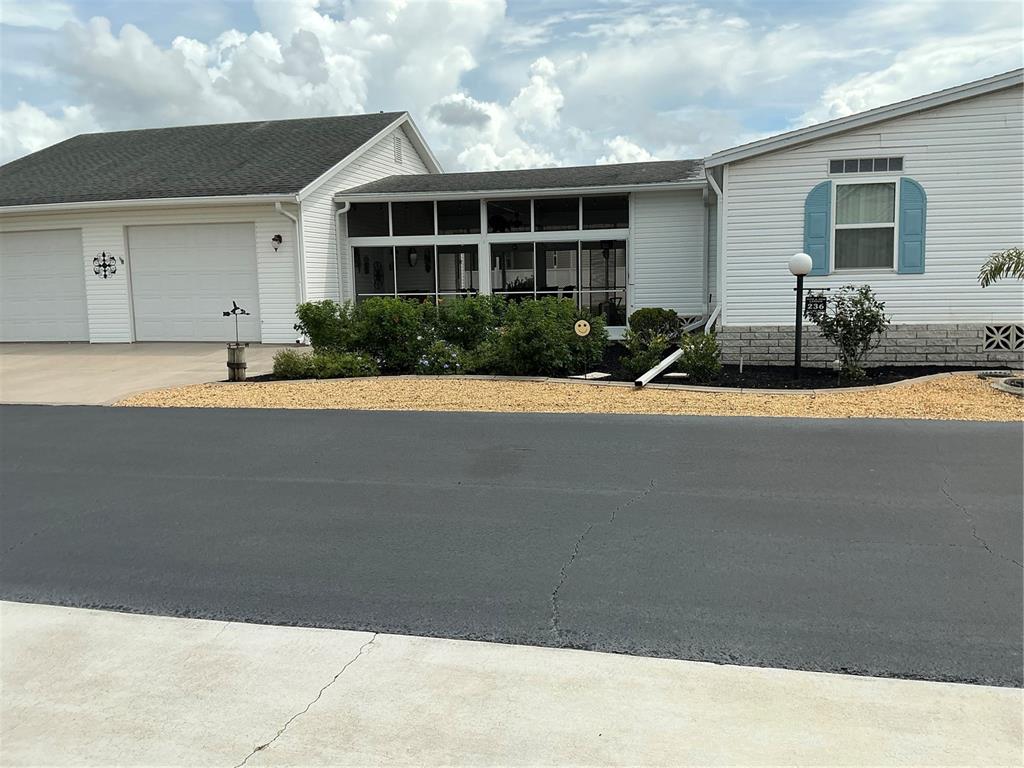 A white house with a two-car garage and a concrete driveway under a cloudy sky — 236 ALLIES PASS PASS UNIT 363, FROSTPROOF, FL