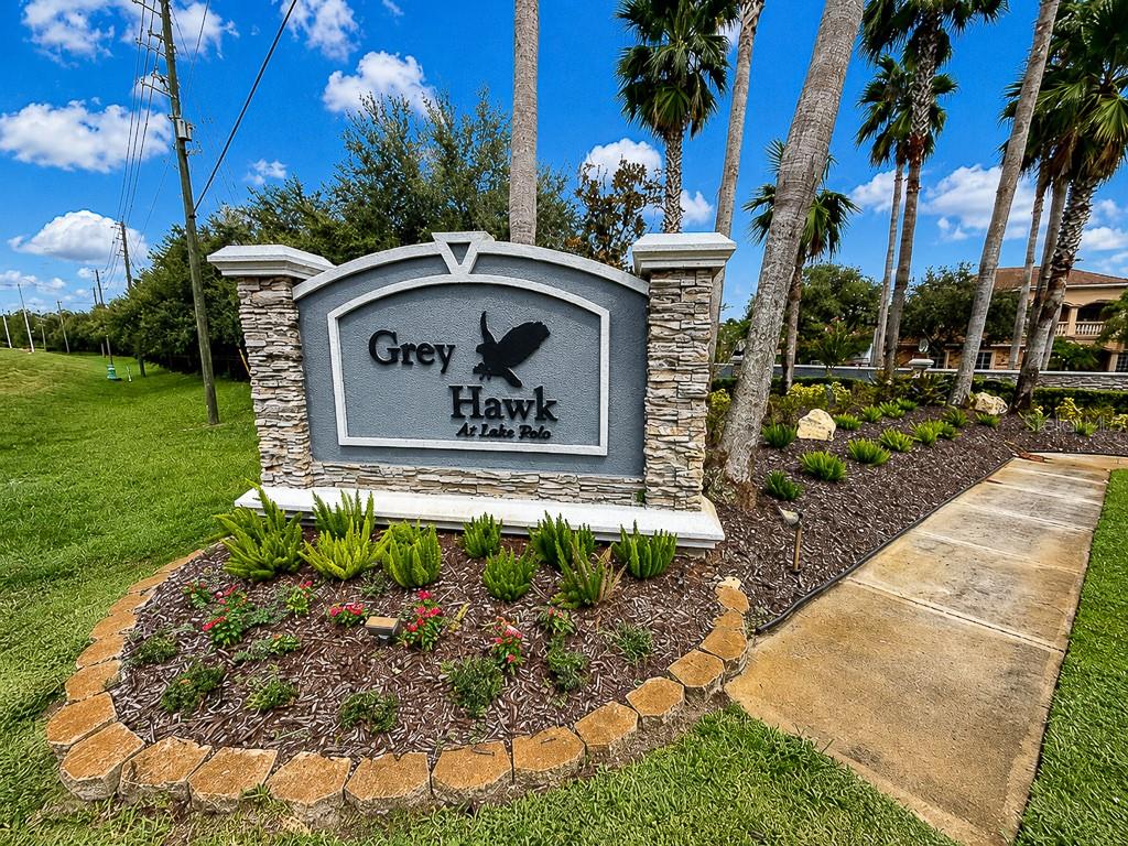 A stone-accented monument sign for Grey Hawk at Lake Polo stands in a landscaped garden — 1637 ABYSS DRIVE, ODESSA, FL