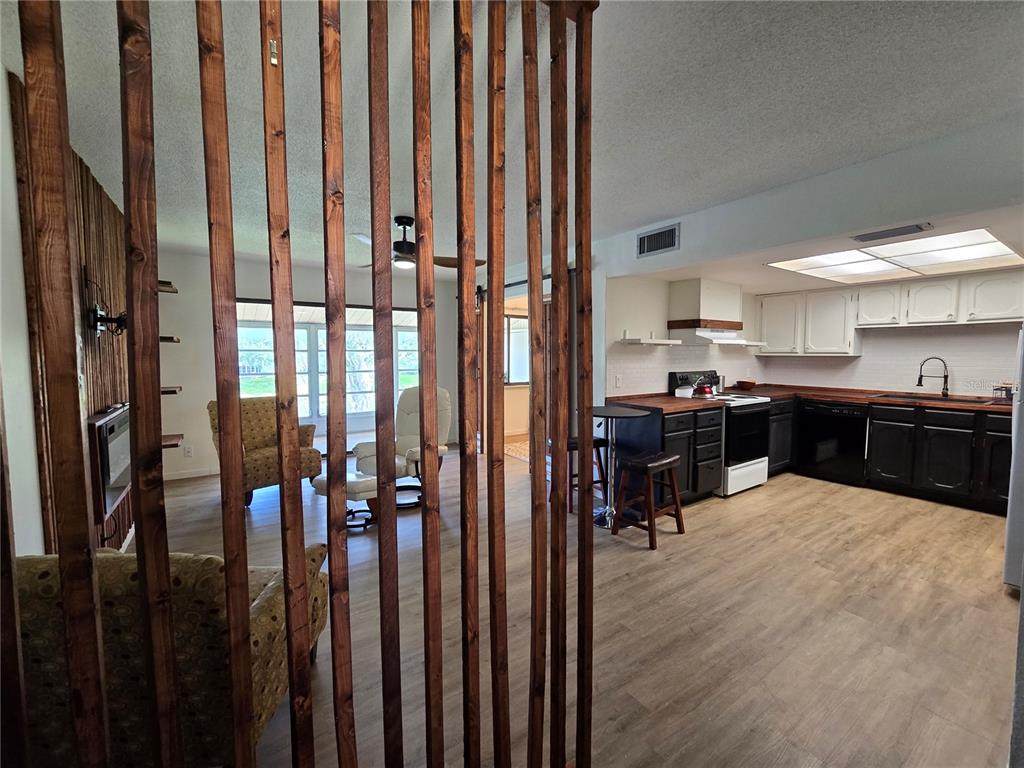 A view through a wooden slat room divider into a kitchen and living area — 623 MIDWAY DRIVE UNIT B, OCALA, FL