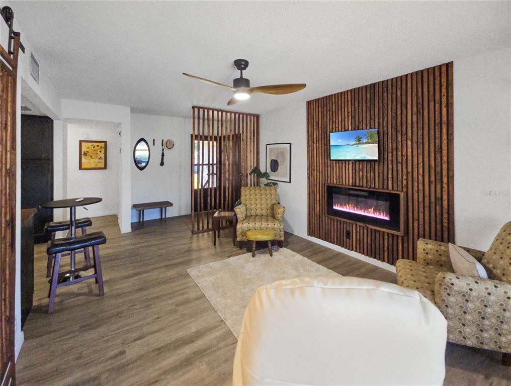 A living room features wood-slat wall paneling, an electric fireplace, and a ceiling fan — 623 MIDWAY DRIVE UNIT B, OCALA, FL