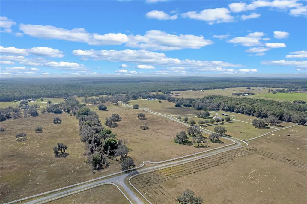 An aerial view shows a large, fenced rural property with scattered trees and gravel roads — 14 EAGLE RIDGE, BUSHNELL, FL
