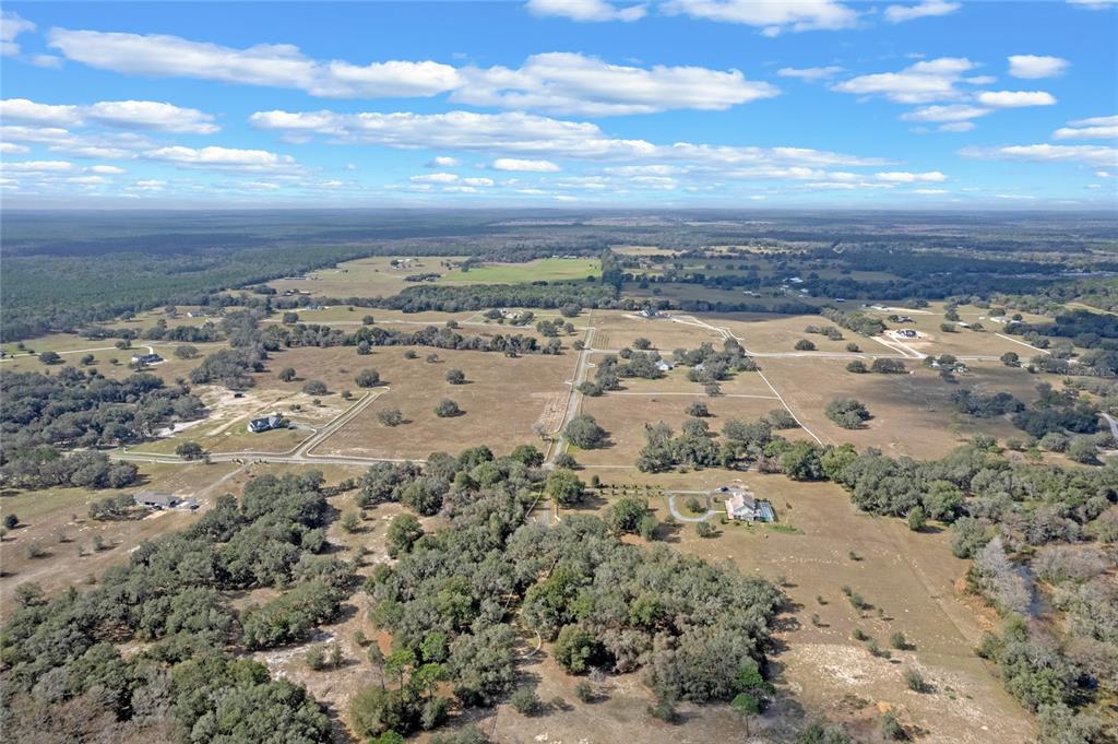 An aerial view shows a rural landscape with scattered houses, pastures, and patches of trees — 14 EAGLE RIDGE, BUSHNELL, FL