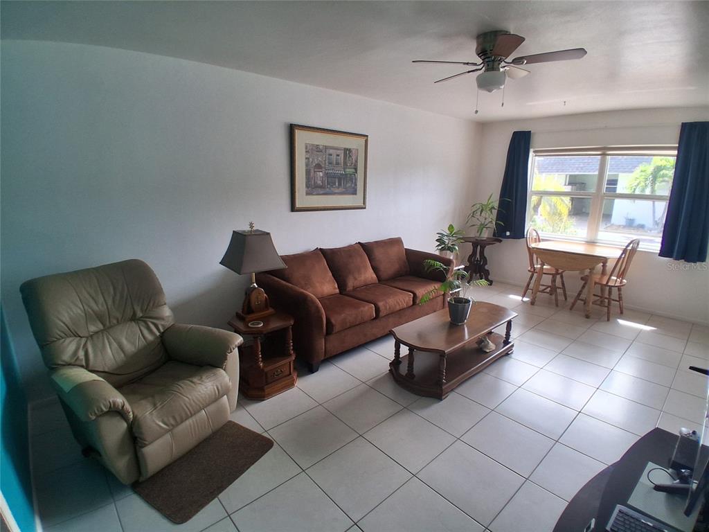 A living room features a brown sofa, a recliner, a coffee table, and a dining area — 125 PORTREE DRIVE, DUNEDIN, FL