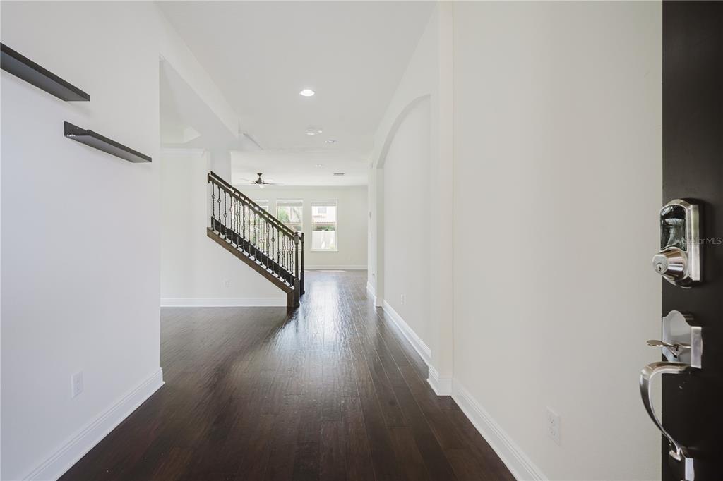 An entryway with dark hardwood floors leads to a staircase with a wrought iron railing — 9072 OVERLOOK PASS DRIVE, WINDERMERE, FL