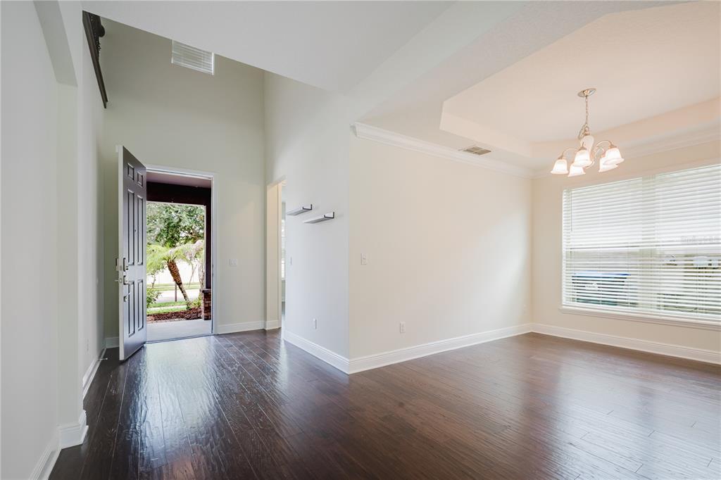 An entryway with dark wood floors leads to a dining room featuring a tray ceiling — 9072 OVERLOOK PASS DRIVE, WINDERMERE, FL