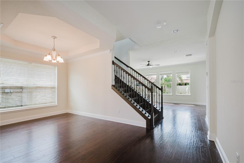 A dining area with a tray ceiling and staircase with dark wood and iron railings — 9072 OVERLOOK PASS DRIVE, WINDERMERE, FL