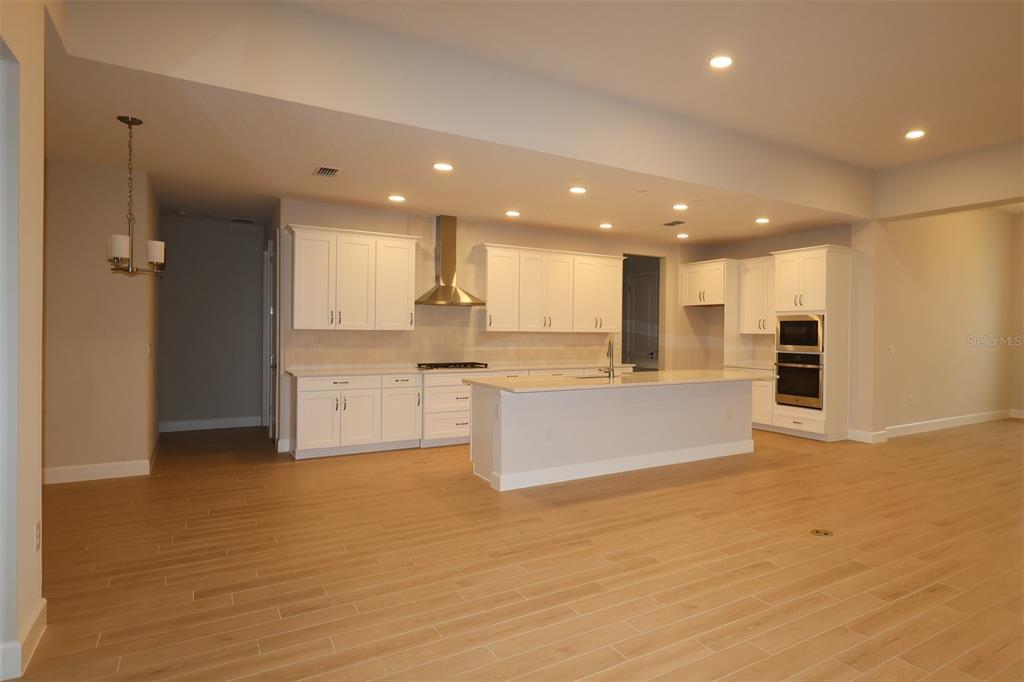 A kitchen under construction features white cabinets, a central island, and light wood flooring — 3223 ROSEVILLE DRIVE, APOPKA, FL