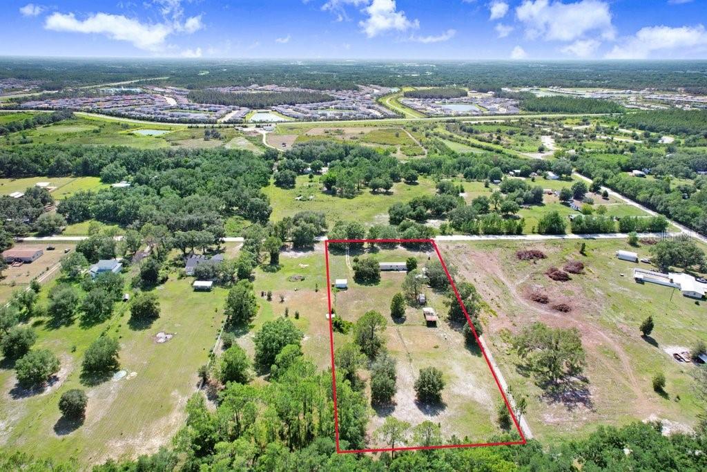 An aerial view shows a rectangular property lot outlined in red containing a small house — 3320 TINA MARIE DRIVE, WESLEY CHAPEL, FL