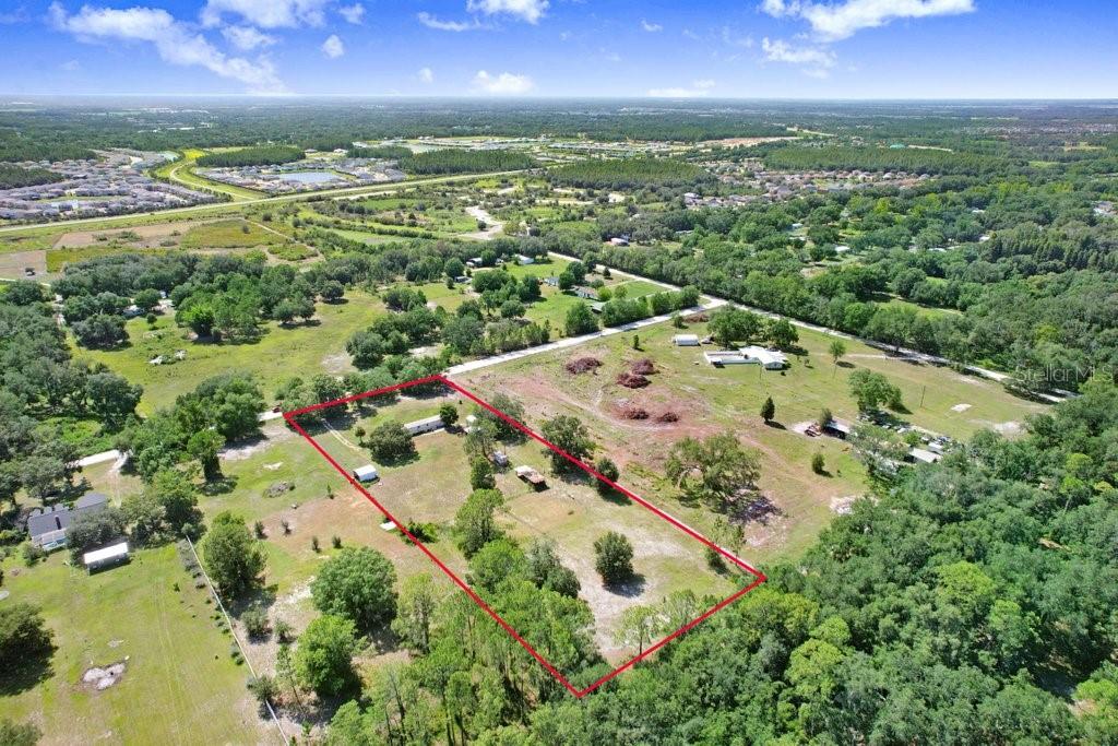 An aerial view shows a rectangular plot of land outlined in red with scattered trees — 3320 TINA MARIE DRIVE, WESLEY CHAPEL, FL