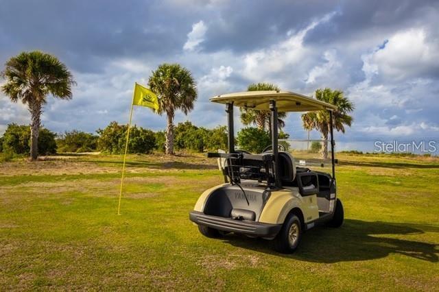 A golf cart sits on a grassy course near a flag under a cloudy sky — 1503 S HIGHLAND PARK DRIVE, LAKE WALES, FL