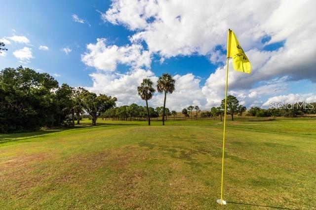 A yellow flag stands on a golf course green with palm trees in the background — 1503 S HIGHLAND PARK DRIVE, LAKE WALES, FL