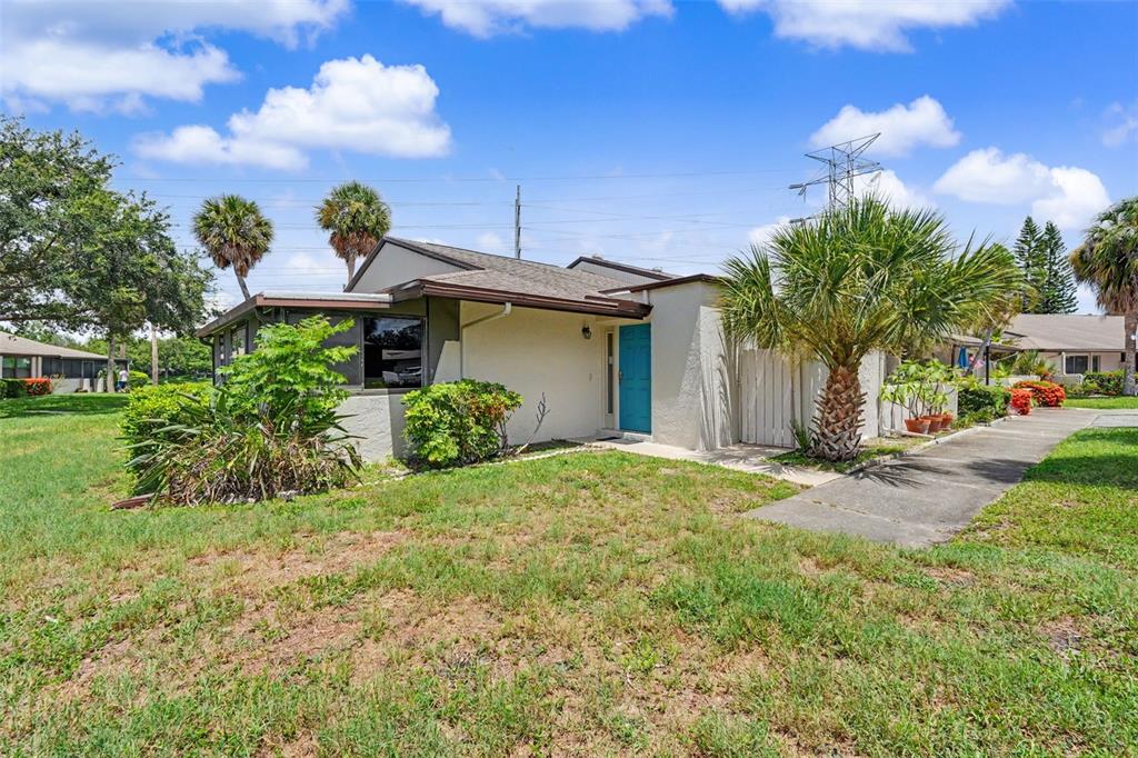 A bright blue front door with a side window sits under an overhanging roof — 1502 16TH CIRCLE SE, LARGO, FL