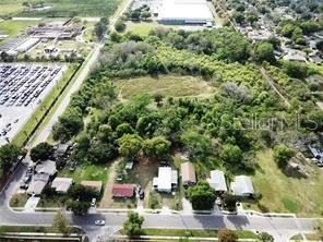 An aerial view shows a wooded lot situated between a parking lot and residential houses — 1211 E MAPLE STREET, WINTER GARDEN, FL