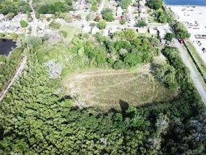 An aerial view shows a vacant, partially wooded lot situated near a residential area and water — 1211 E MAPLE STREET, WINTER GARDEN, FL