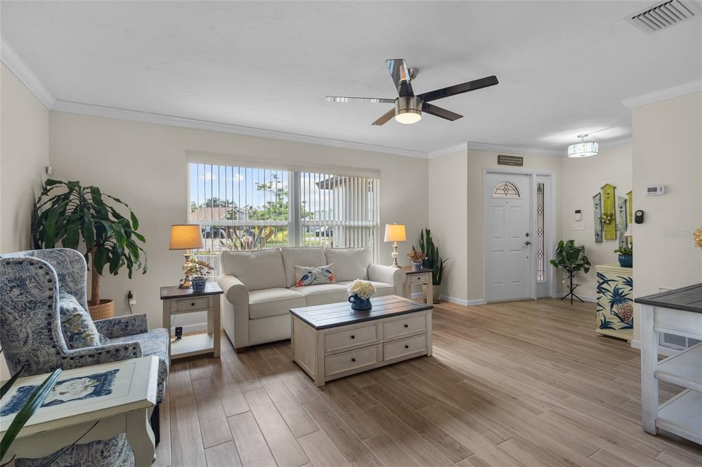 A living room features a white sofa, a coffee table, and wood-look tile flooring — 6640 WATERFORD LANE, SARASOTA, FL