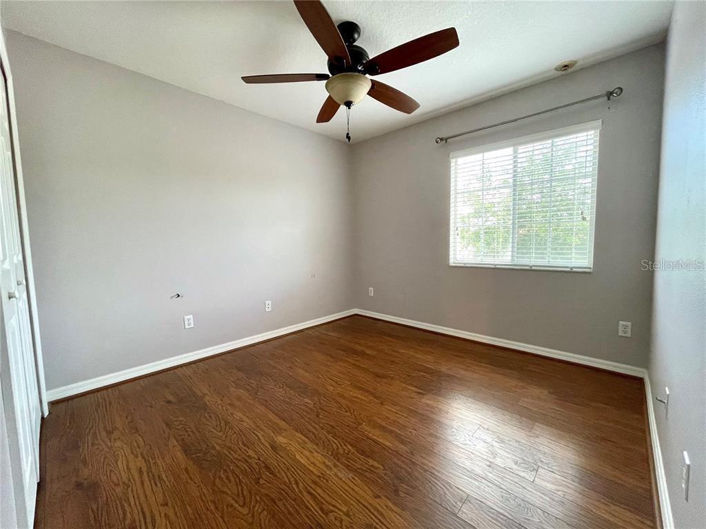 An empty bedroom features light gray walls, a ceiling fan, and dark wood flooring — 5083 FIORELLA LANE, SANFORD, FL