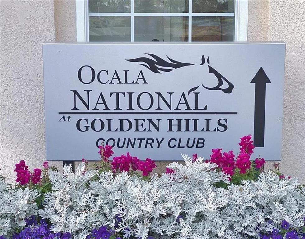 A sign for Ocala National at Golden Hills Country Club sits behind a flower bed — 7699 NW 56TH PLACE, OCALA, FL