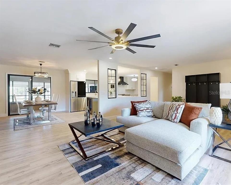 An open-concept living and dining area features light wood flooring and a modern ceiling fan — 7699 NW 56TH PLACE, OCALA, FL
