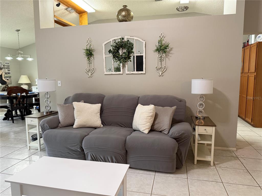 A concrete walkway leads to a screened entryway with a white chair and potted plants — 908 45TH STREET E, BRADENTON, FL