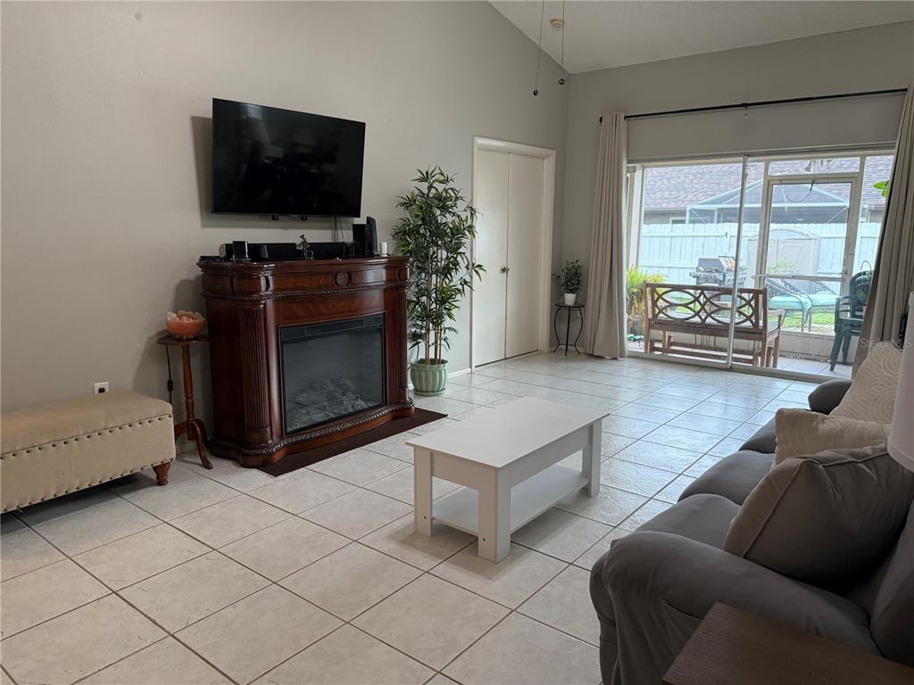A view through a screen door shows a patio with potted plants and landscaping — 908 45TH STREET E, BRADENTON, FL