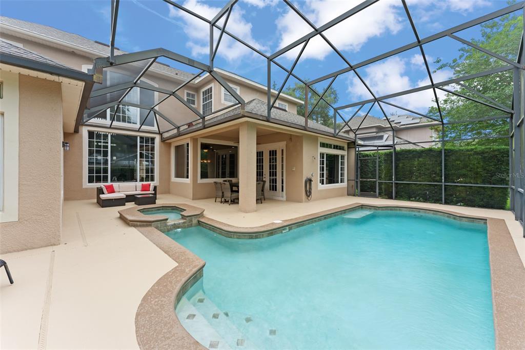 A screened-in patio features a swimming pool, a raised spa, and outdoor furniture — 14411 HAMPSHIRE BAY CIRCLE, WINTER GARDEN, FL