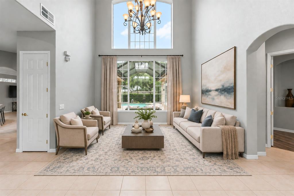 A high-ceilinged living room features two beige sofas, a central rug, and a large window — 14411 HAMPSHIRE BAY CIRCLE, WINTER GARDEN, FL