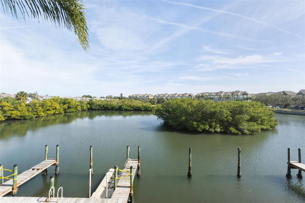 A view of a calm waterway with wooden docks and a mangrove island under blue skies — 8806 BAY POINTE DRIVE UNIT 206, TAMPA, FL