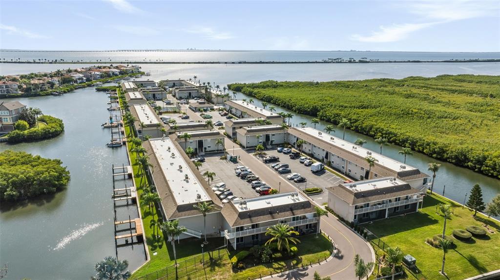 An aerial view shows a multi-building apartment complex situated along a waterway and mangroves — 8806 BAY POINTE DRIVE UNIT 206, TAMPA, FL