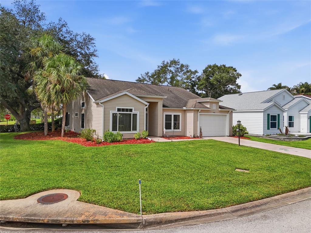A tan, single-story suburban house with a white garage and a green lawn — 5350 ASTOR STREET, LEESBURG, FL
