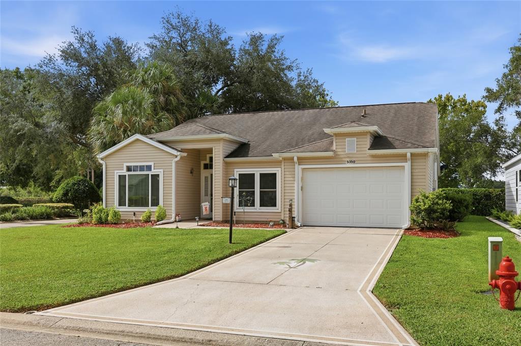 A single-story house with tan siding, a two-car garage, and a concrete driveway — 5350 ASTOR STREET, LEESBURG, FL