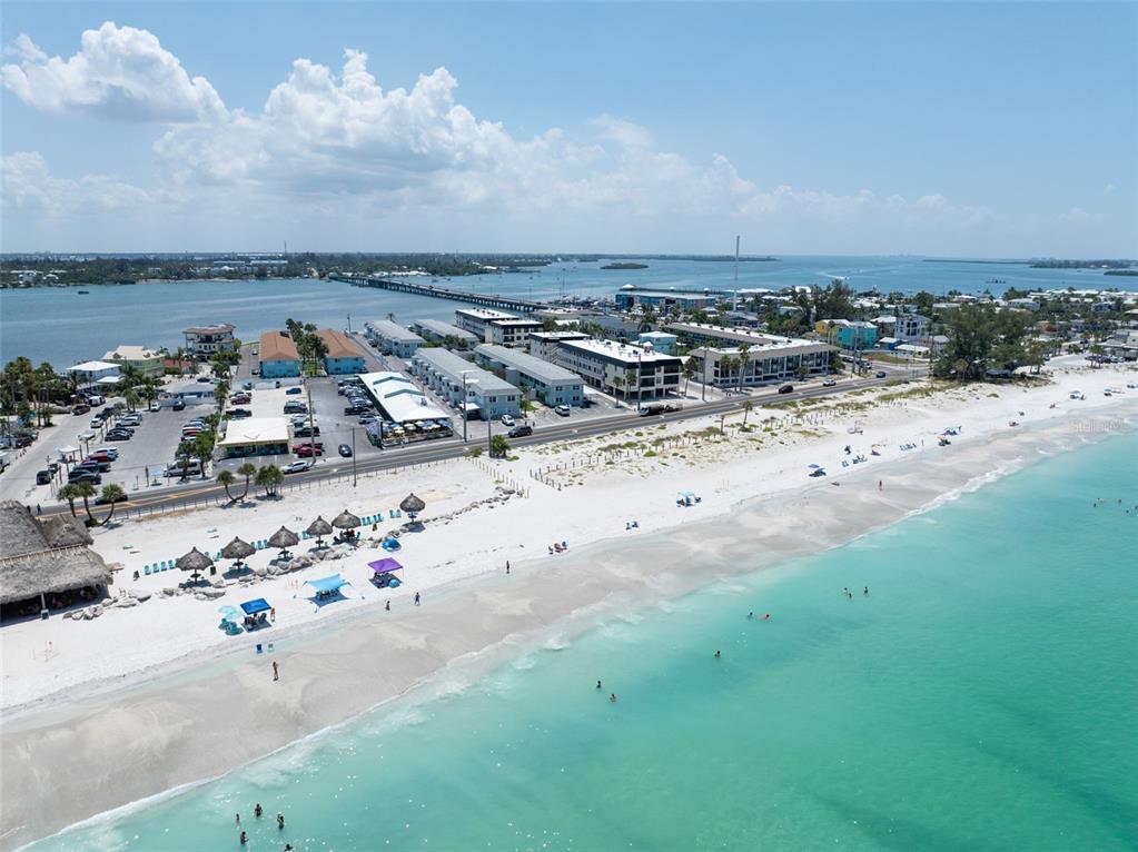 An elevated view from a balcony overlooks a swimming pool and palm trees — 611 GULF DRIVE N UNIT C27, BRADENTON BEACH, FL
