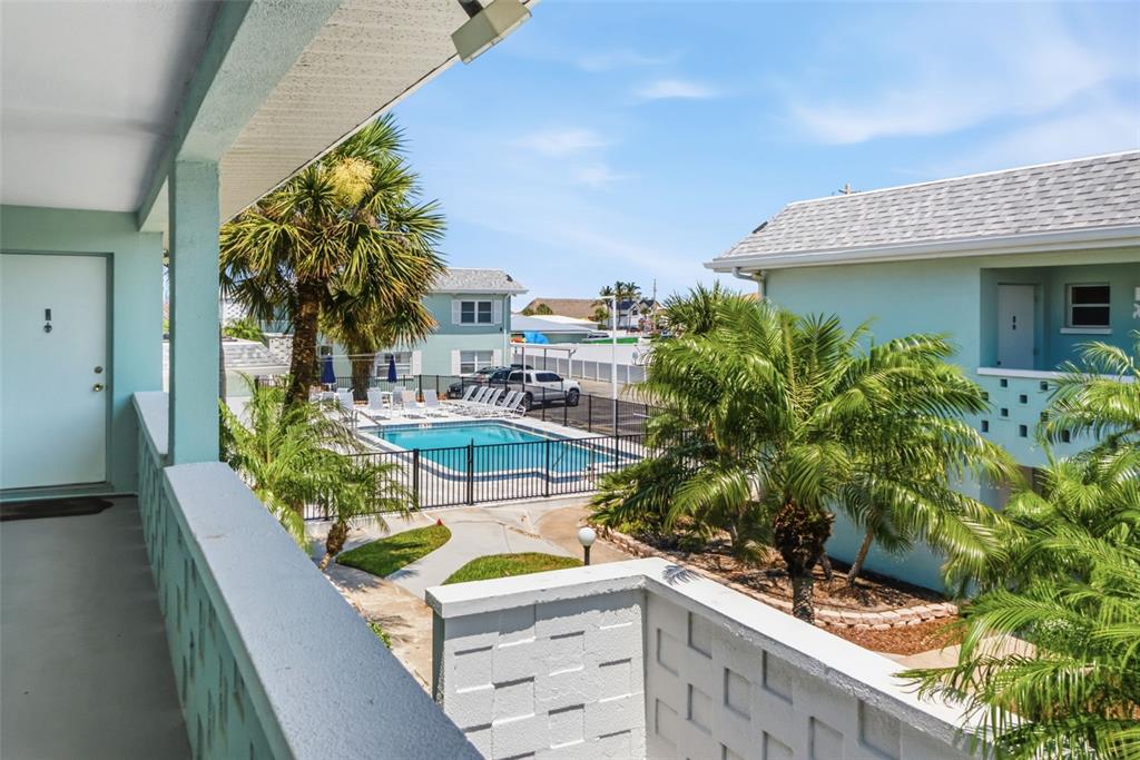 An outdoor swimming pool with a shallow entry area sits beside a light-colored building — 611 GULF DRIVE N UNIT C27, BRADENTON BEACH, FL
