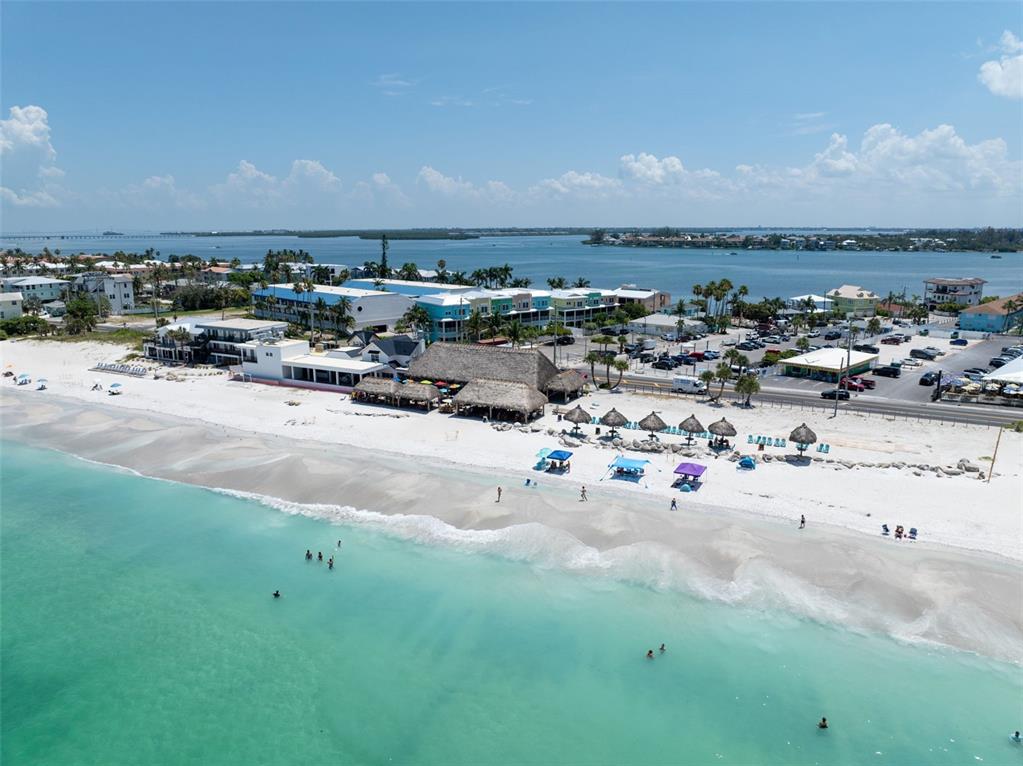 A paved patio with a tree and seating overlooks a bay with a flag — 611 GULF DRIVE N UNIT C27, BRADENTON BEACH, FL