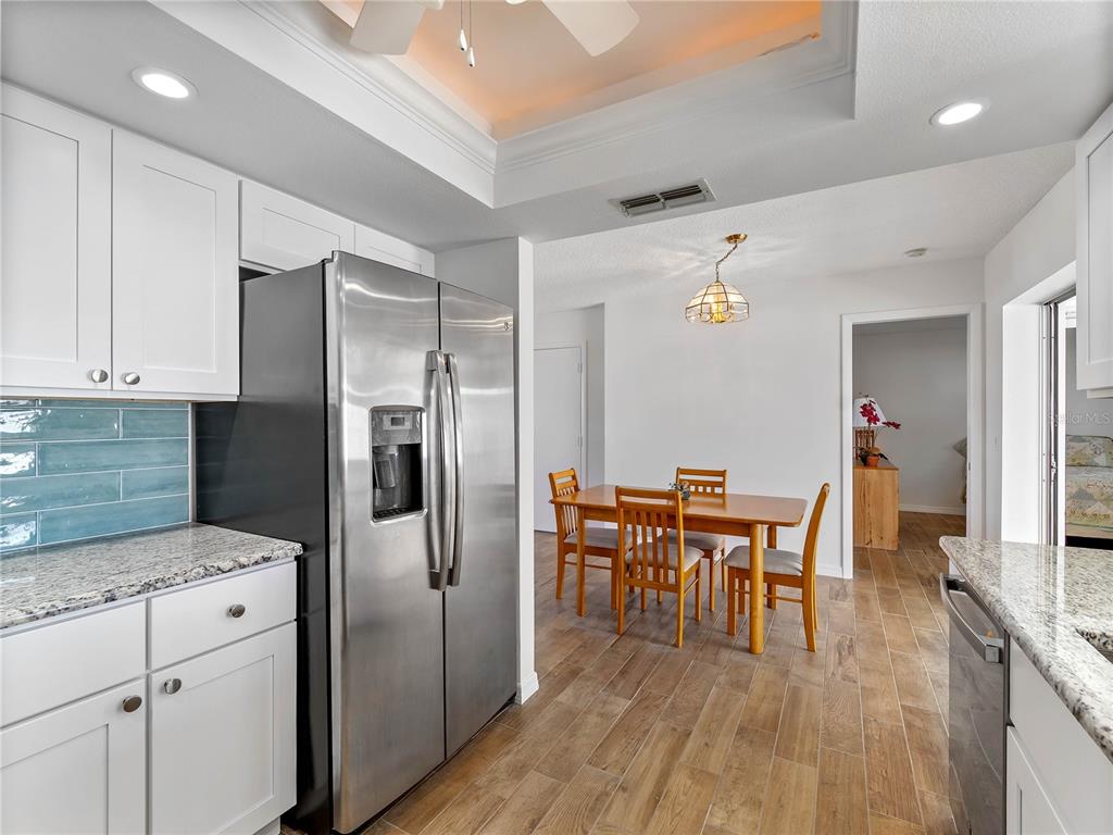 A kitchen with white cabinets, stainless steel appliances, and a dining area with wood floors — 52 CIRCLEWOOD DRIVE UNIT A1-2, VENICE, FL