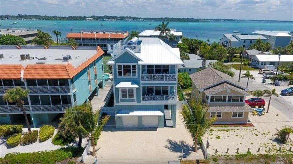 An aerial view of a three-story blue house situated between two other residential buildings — 903 GULF DRIVE S, BRADENTON BEACH, FL