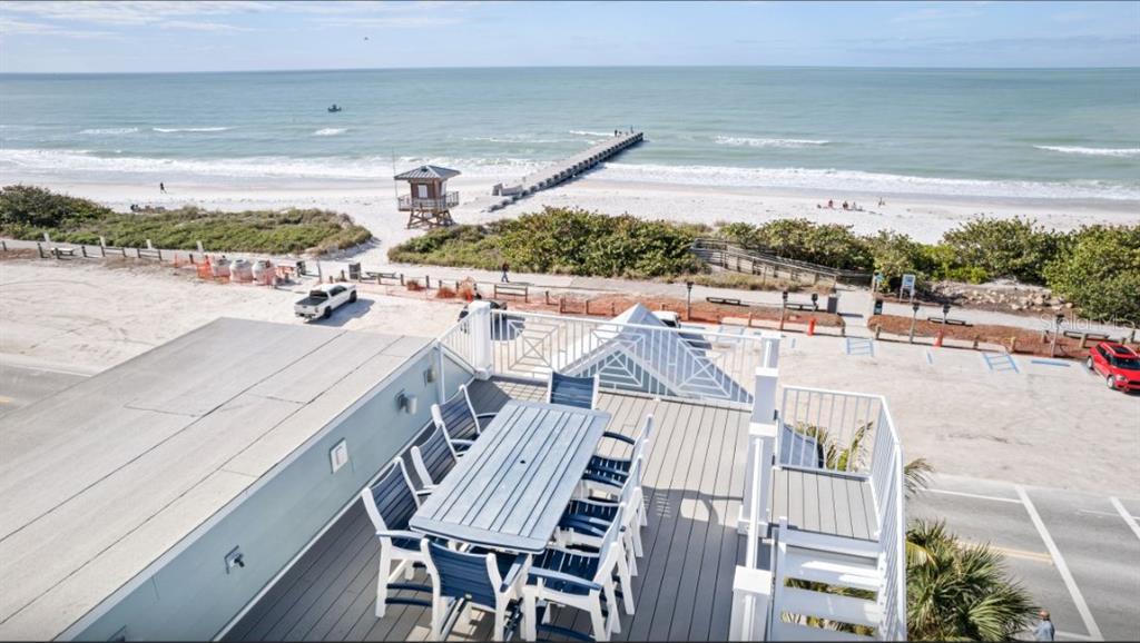 An elevated deck features a dining set overlooking a beach, ocean, and fishing pier — 903 GULF DRIVE S, BRADENTON BEACH, FL