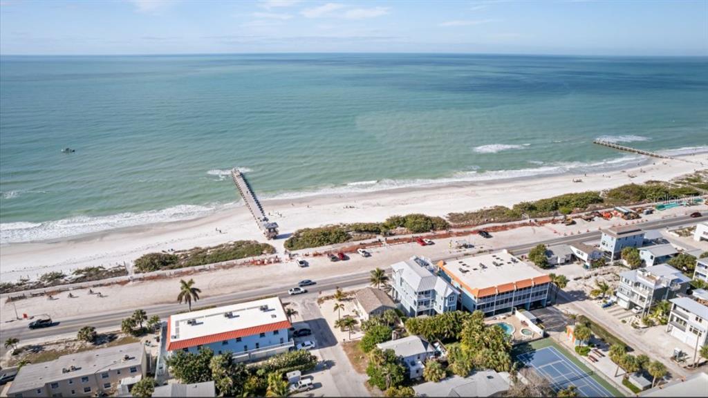 An aerial view of a beach with a pier, coastal road, and nearby residential buildings — 903 GULF DRIVE S, BRADENTON BEACH, FL