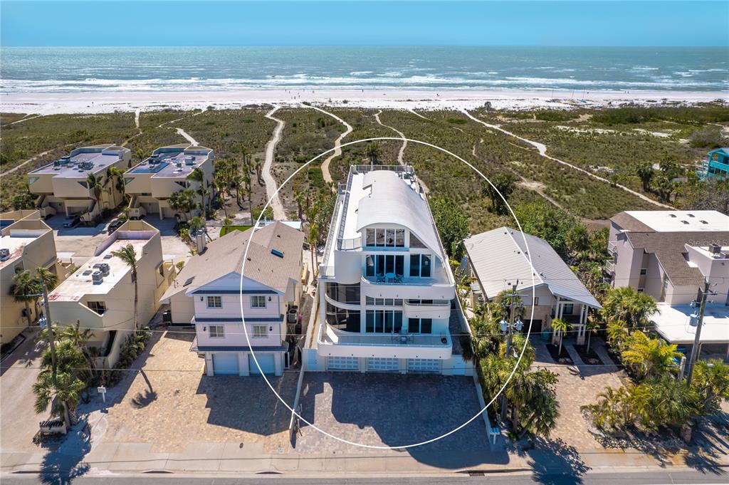 A three-story white modern beach house features large glass windows and balconies facing a sandy path — 534 BEACH ROAD, SARASOTA, FL