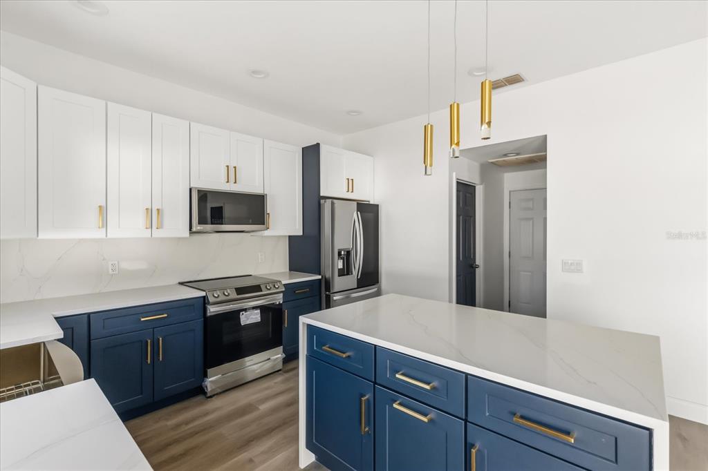 A kitchen features blue lower cabinets, white upper cabinets, a kitchen island, and gold hardware — 15663 DURANGO CIRCLE, BROOKSVILLE, FL