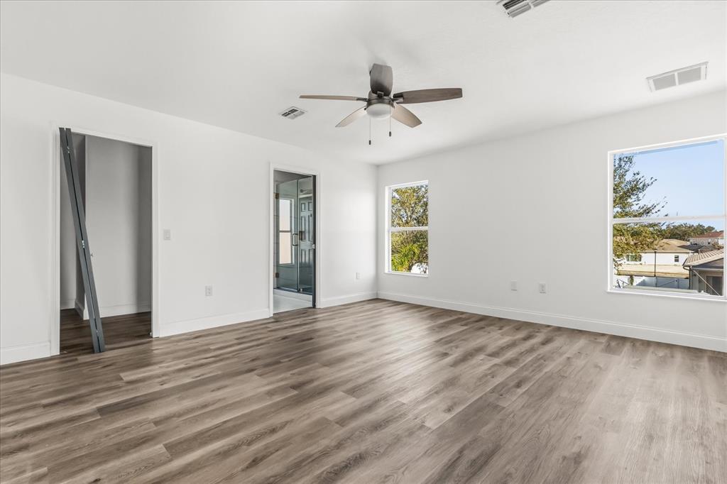 An empty bedroom features white walls, wood-look flooring, a ceiling fan, and two windows — 15663 DURANGO CIRCLE, BROOKSVILLE, FL