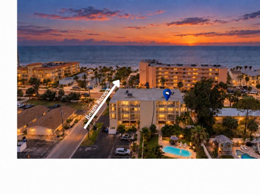 An aerial view shows a multi-story apartment building with a pool and nearby beach access — 1005 GULF BOULEVARD UNIT 10, INDIAN ROCKS BEACH, FL