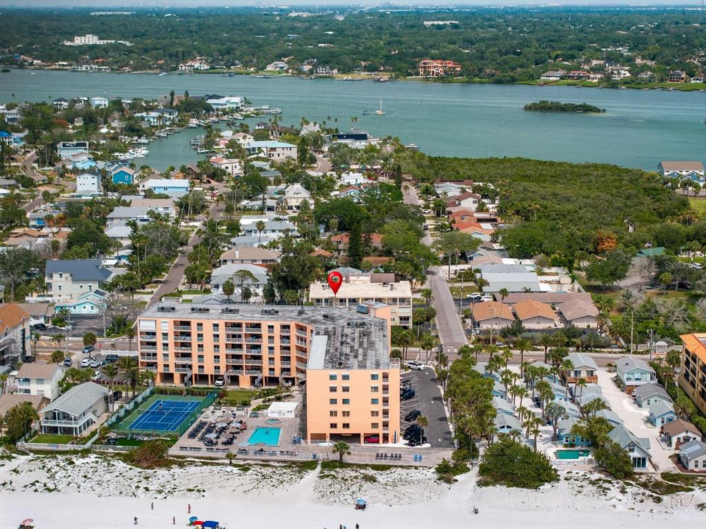 A balcony with chairs overlooks a street, palm trees, and the ocean in the distance — 1005 GULF BOULEVARD UNIT 10, INDIAN ROCKS BEACH, FL