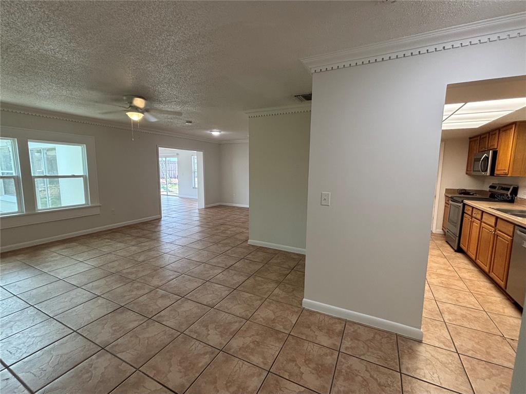 An open-concept living area with tile flooring leads to a kitchen with wood cabinets — 103 BILSDALE COURT, LONGWOOD, FL
