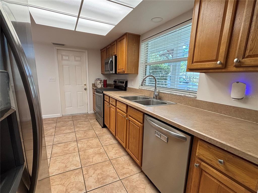 A kitchen features wood cabinets, stainless steel appliances, a double sink, and tile flooring — 103 BILSDALE COURT, LONGWOOD, FL