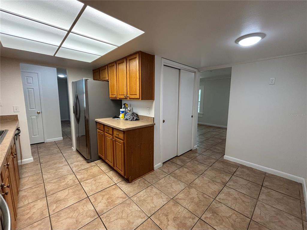 A kitchen features wood cabinets, stainless steel appliances, and tile flooring under a recessed light — 103 BILSDALE COURT, LONGWOOD, FL